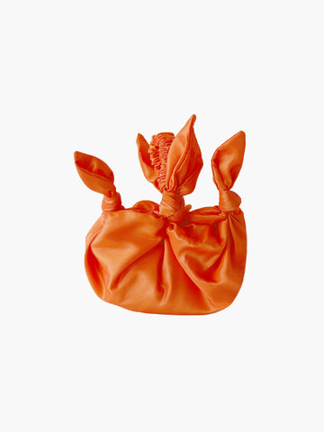 Orange taffeta knotted bag with ruched handle on a white background