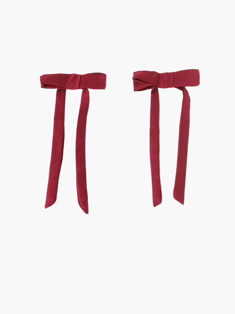 Pair of burgundy satin bow hair clips on a white background
