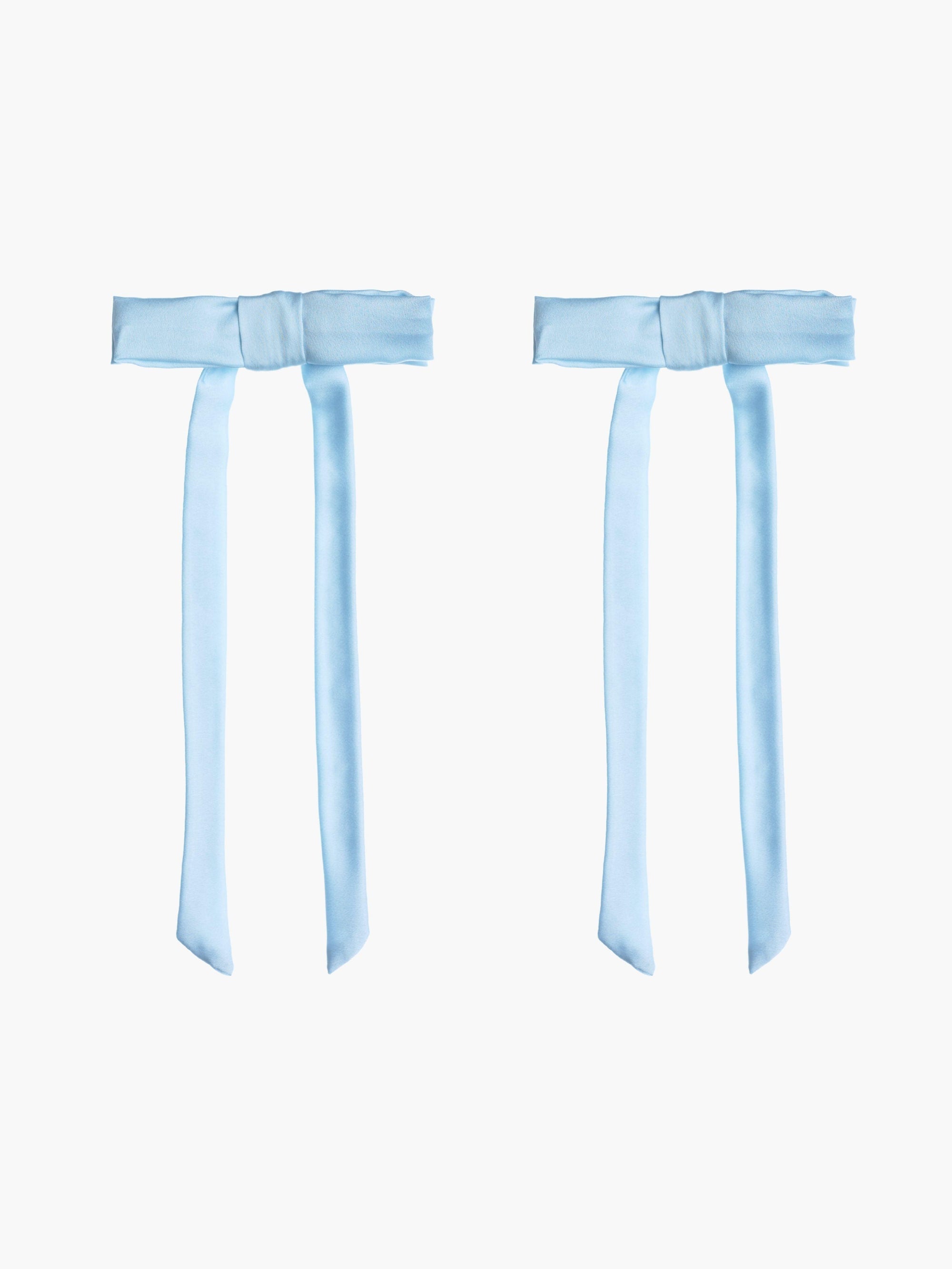 Two light blue satin hair bow clips together on a white background