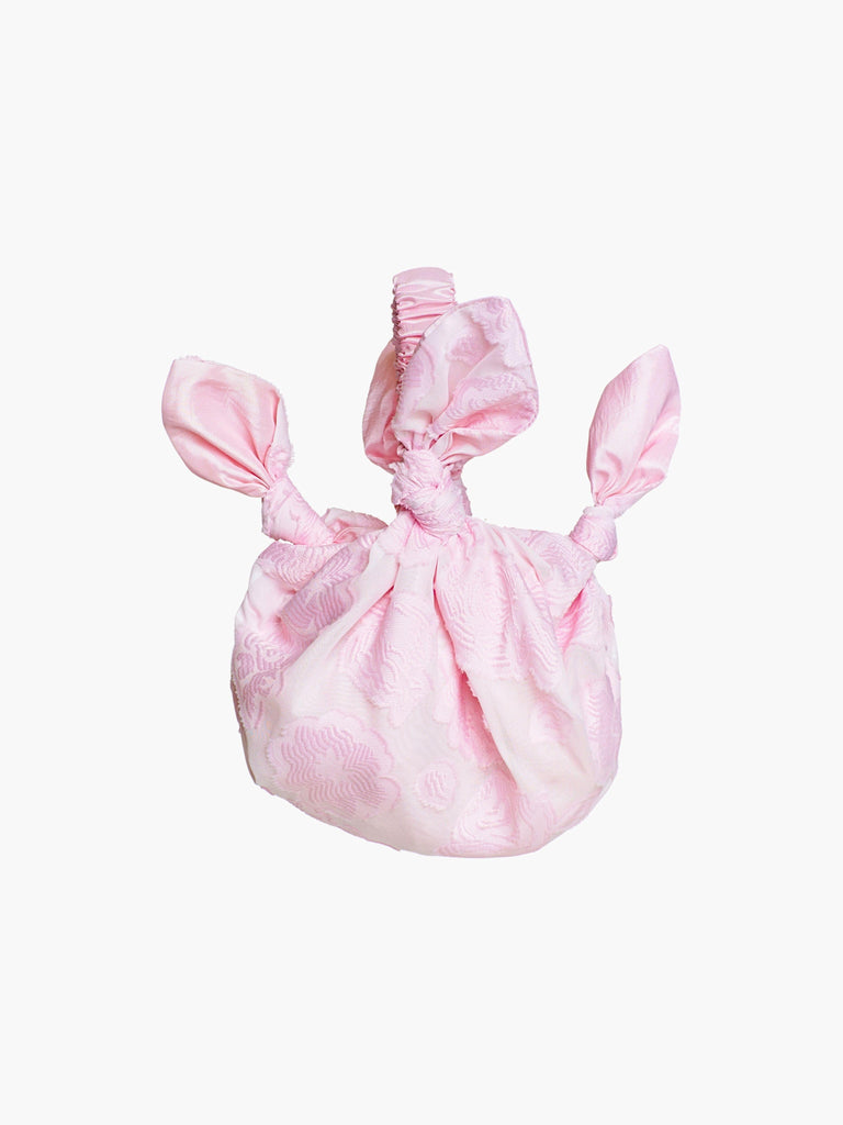 Pink floral knotted handbag on a white background