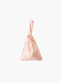 Peach satin knot bag against a plain white background. The elegant bag has a twisted handle and sleek, glossy fabric, exuding a chic, minimalist style.
