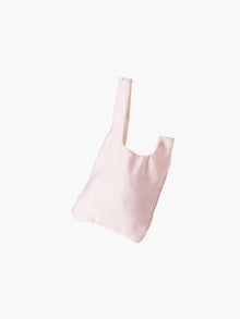 Pink satin knot bag against a plain white background. The elegant bag has a twisted handle and sleek, glossy fabric, exuding a chic, minimalist style.