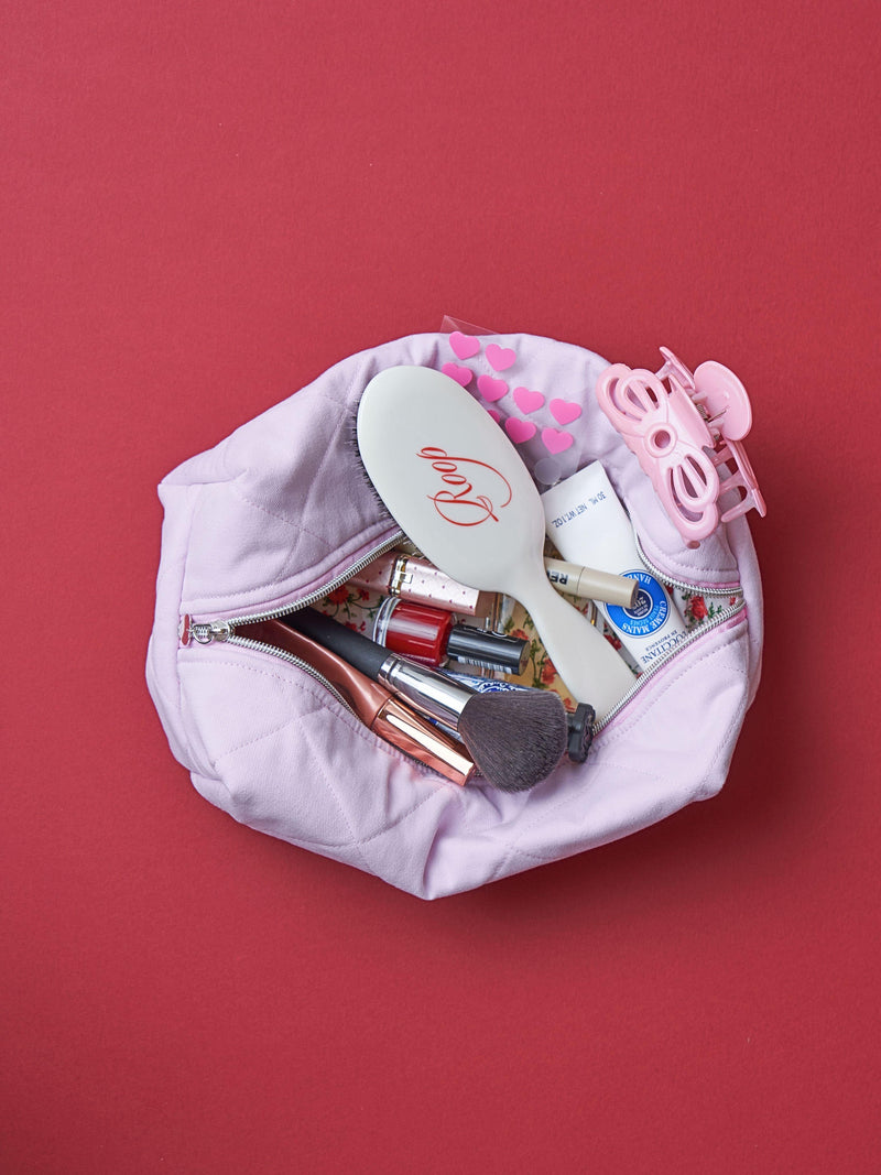 Pink makeup bag with cosmetic items on a red background