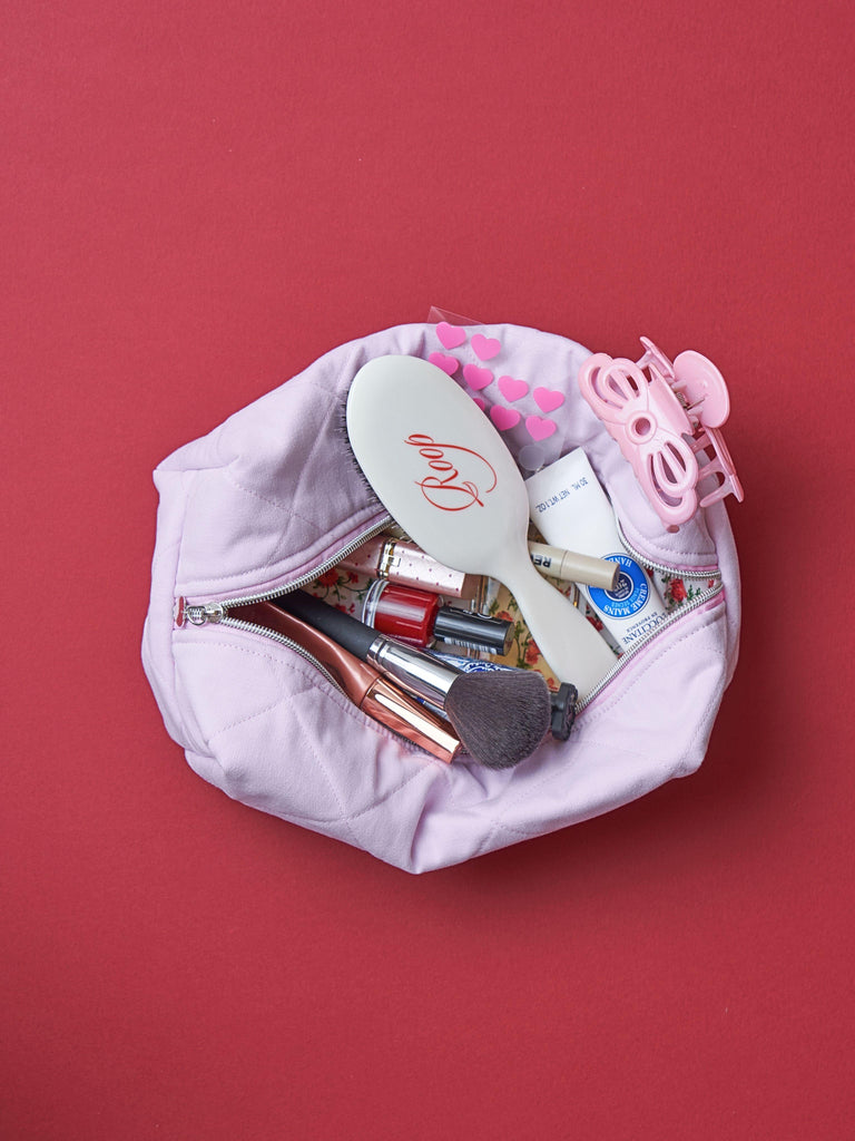 Pink makeup bag with cosmetic items on a red background