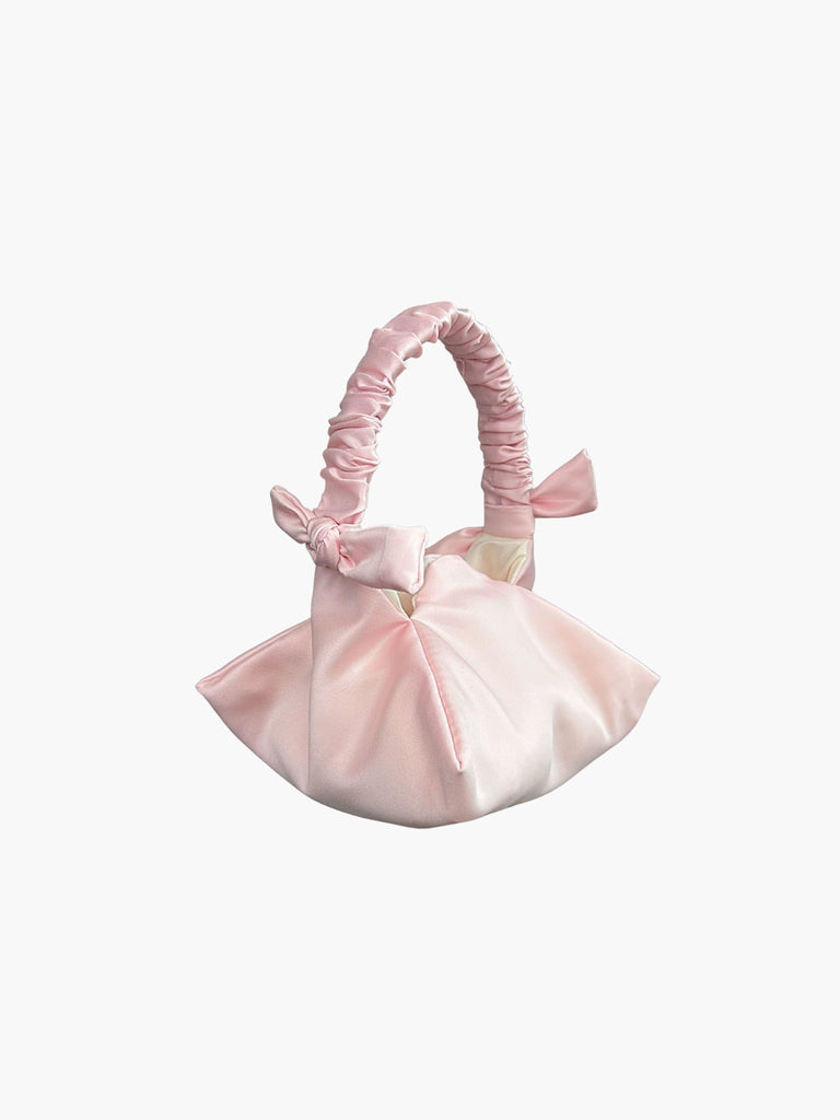 pink satin ruched handle handbag with decorative bows, set on a white background