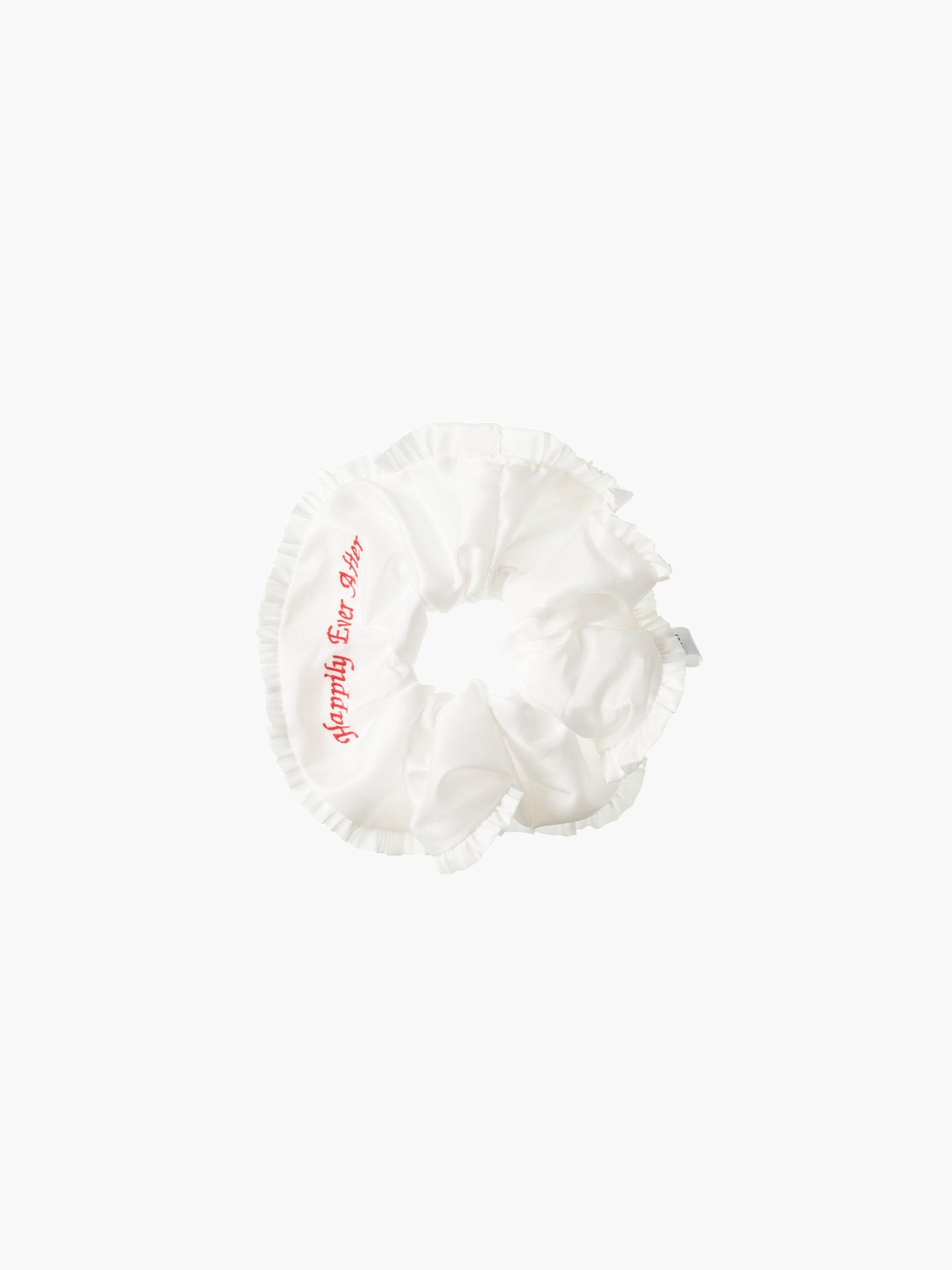 Ivory ruffled scrunchie with red embroidery that reads 'happily ever after' on a white background