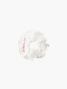 Ivory ruffled scrunchie with red embroidery that reads 'happily ever after' on a white background