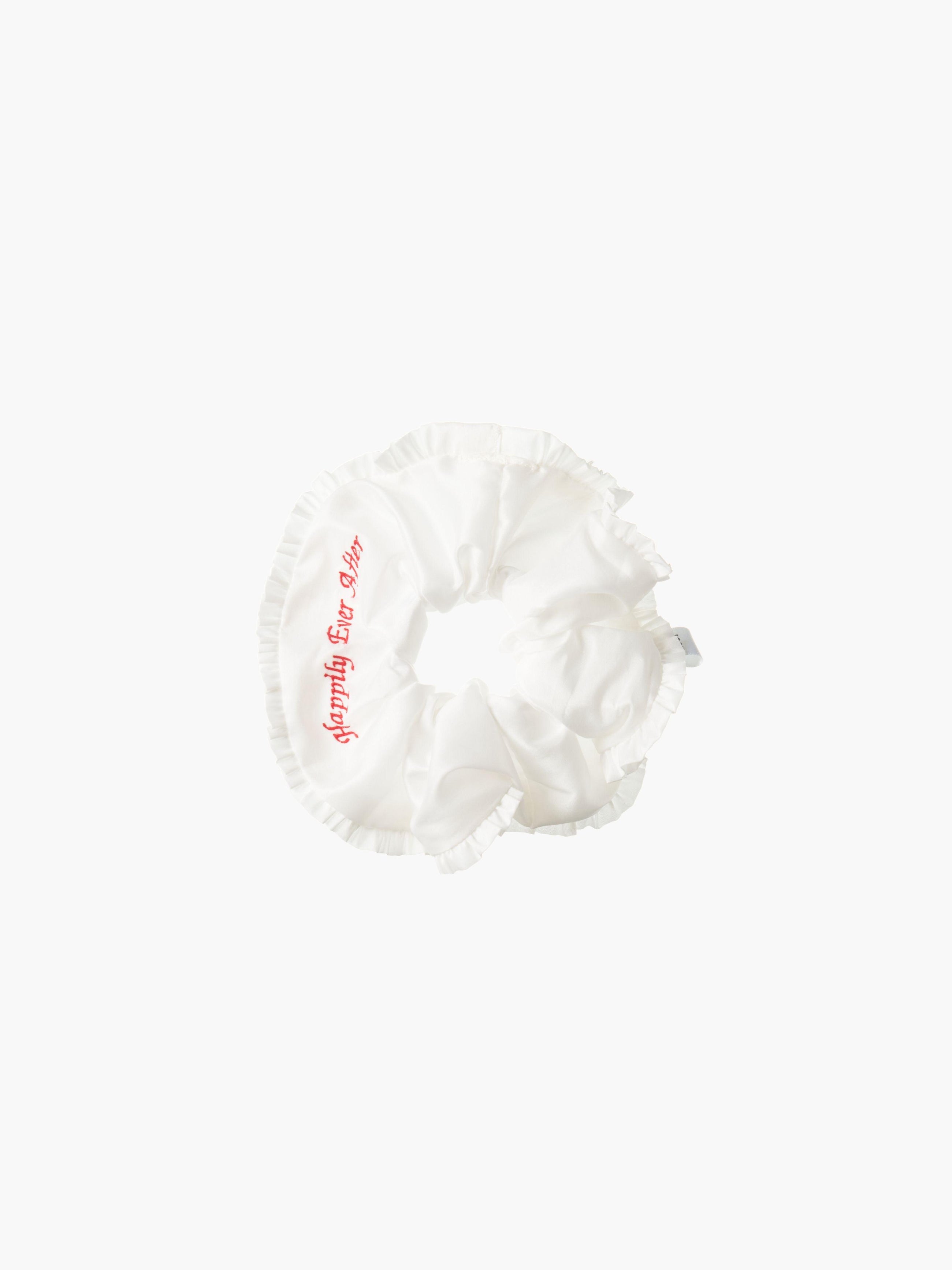 Ivory ruffled scrunchie with red embroidery that reads 'happily ever after' on a white background