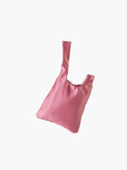 Rose satin knot bag against a plain white background. The elegant bag has a twisted handle and sleek, glossy fabric, exuding a chic, minimalist style.
