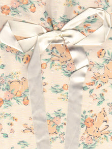 Close up of a floral and rabbit print fabric pouch, tied with an ivory ribbon.
