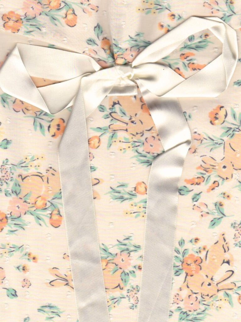 Close up of a floral and rabbit print fabric pouch, tied with an ivory ribbon.