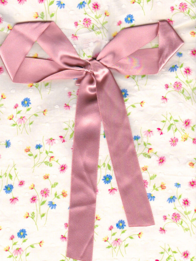 Close up of cream floral patterned fabric envelope pouch tied with a pink ribbon.