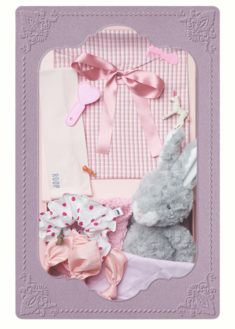pink checkered ribbon tied pouch, with a pink headband, polka dot white and pink scrunchie, and grey rabbit teddy, inside a lilac frame.