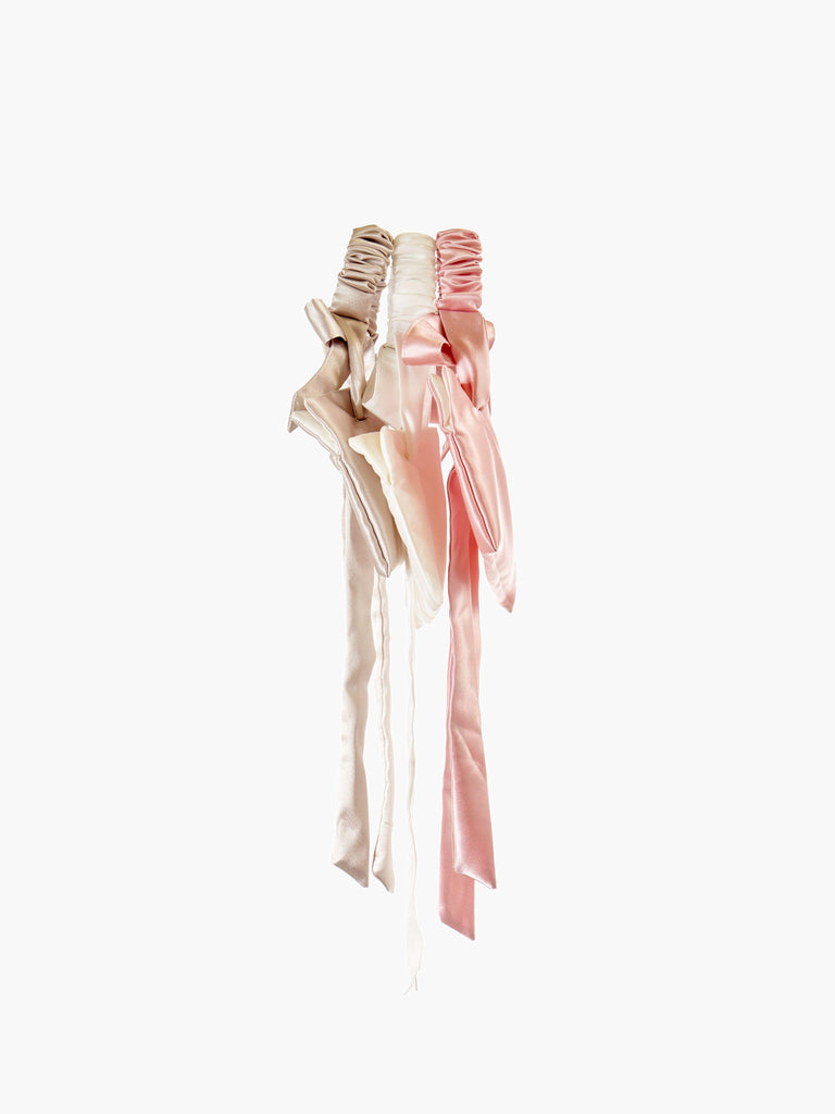 three satin wristlet bags in taupe, ivory and pink.