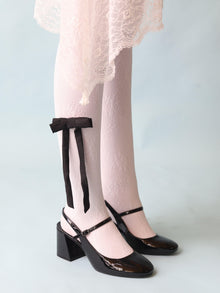 Person wearing a white lace skirt, white lace tights and black high-heeled mary jane shoes styled with a black satin hair bow clip clipped on the tights, set on a light blue background, 