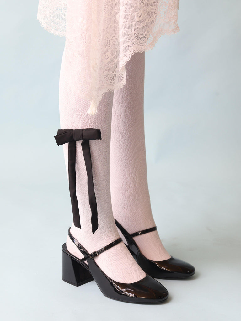 Person wearing a white lace skirt, white lace tights and black high-heeled mary jane shoes styled with a black satin hair bow clip clipped on the tights, set on a light blue background, 