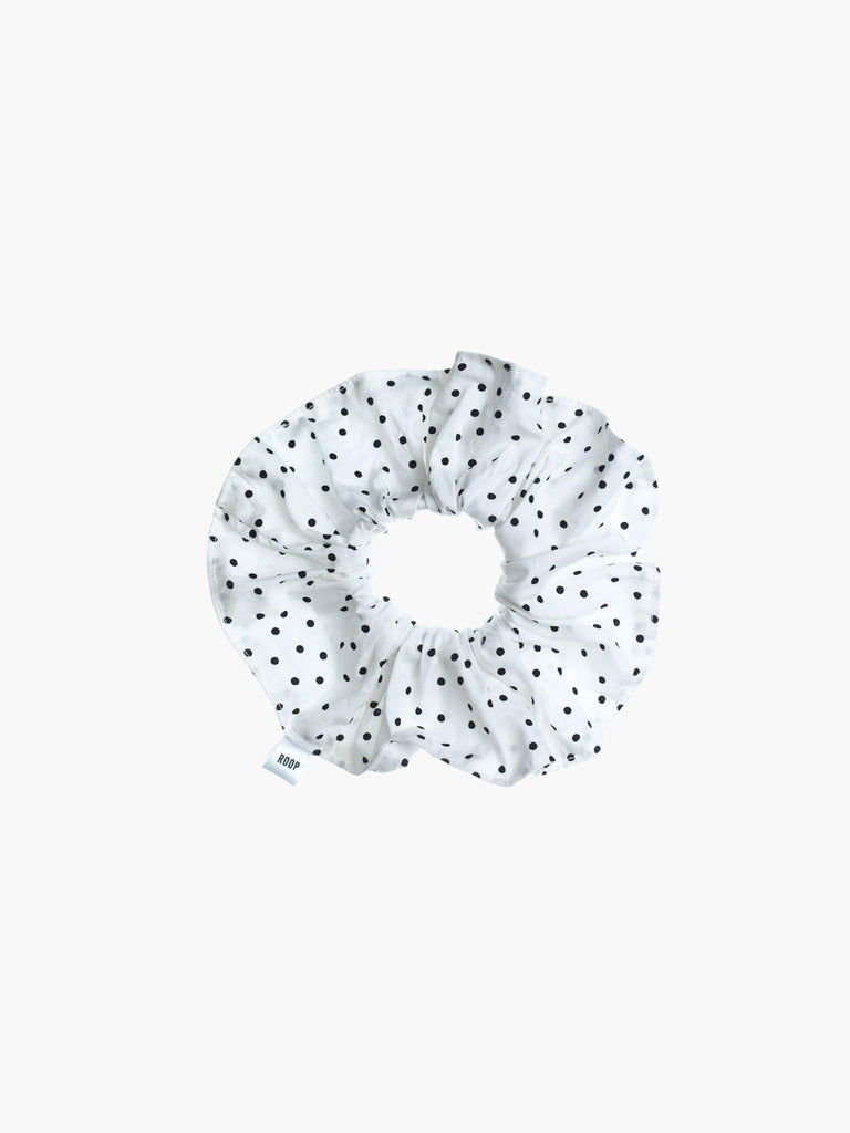 White scrunchie with black polka dots on a white background