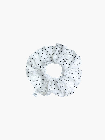 White scrunchie with black polka dots on a white background