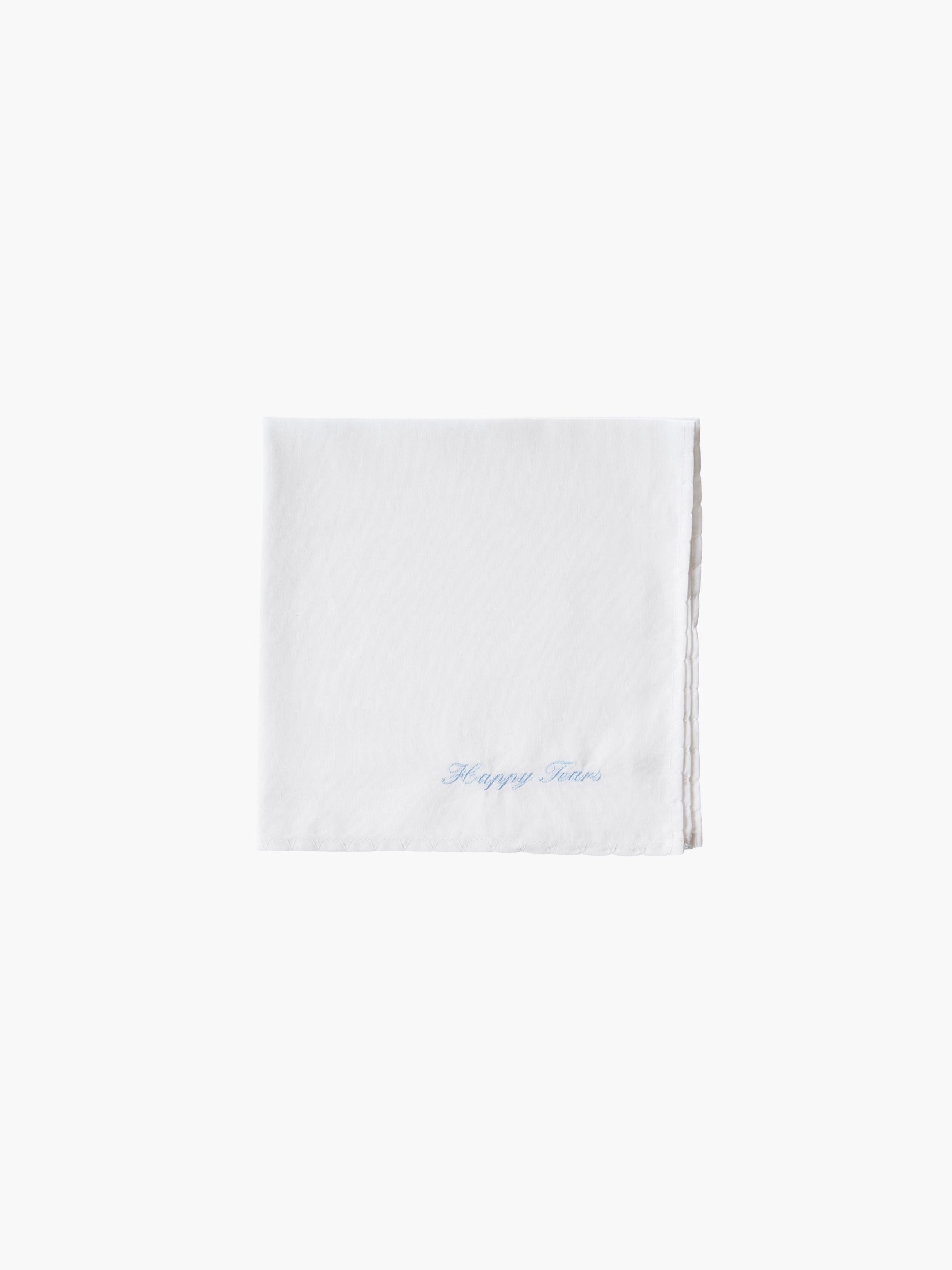 A white cotton embroidered square handkerchief, embroidered with "happy tears" in blue.