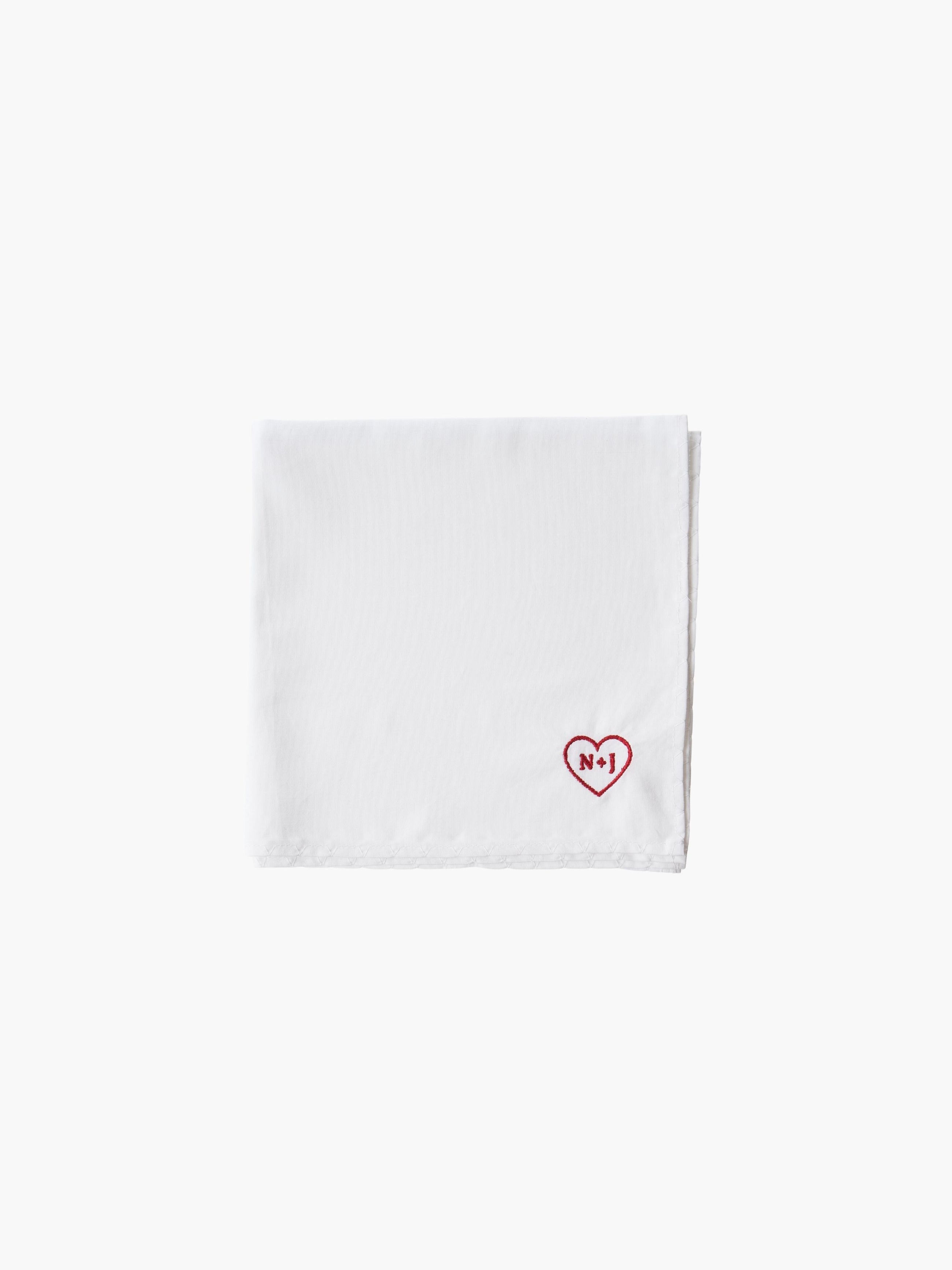 A white cotton embroidered square handkerchief, embroidered with initials inside a red heart, using red thread.