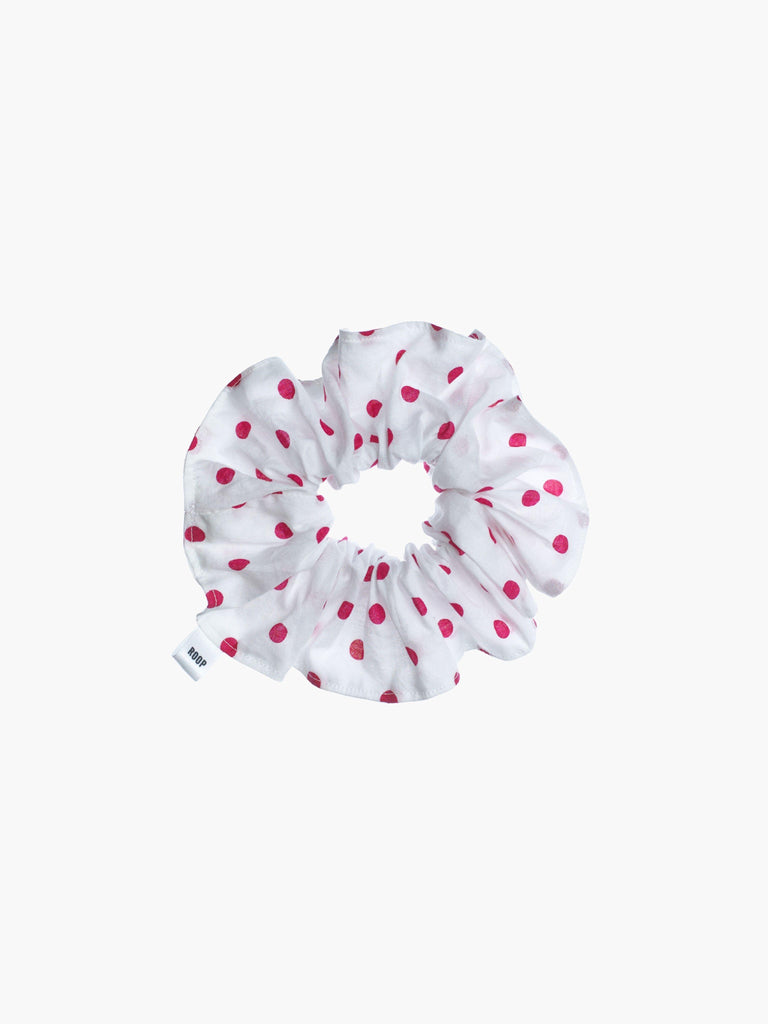 White scrunchie with pink polka dots on a white background